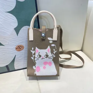 Close-up of a stylish knitted crossbody phone bag with a cute white cat pattern