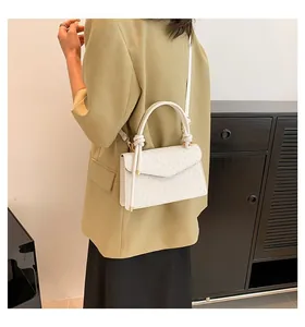 White retro small square flap bag shown as a shoulder bag on model. Detail view.