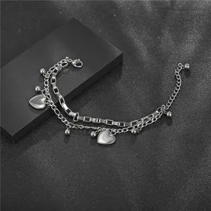 Bracelet double couche en acier inoxydable avec cœurs et perles sur fond noir.