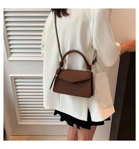 Detailed view of a brown vintage-style textured flap crossbody bag worn by a model