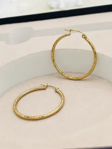 Detailed view of the elegant striped texture on these 24K gold-plated hoop earrings.