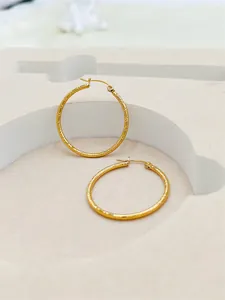Close-up of elegant large 24K gold plated hoop earrings with a textured striped design.
