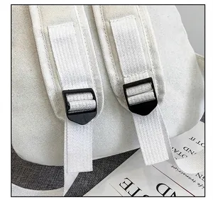 Close-up detail view of durable white canvas backpack shoulder straps and black buckles