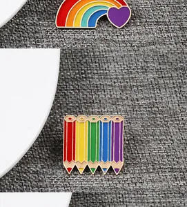 Macro detail of creative colorful enamel rainbow heart and pencil badges with gold trim