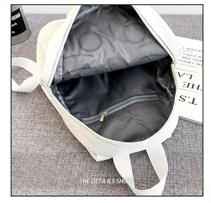 Close-up of the grey interior lining and zipper pocket of the white backpack