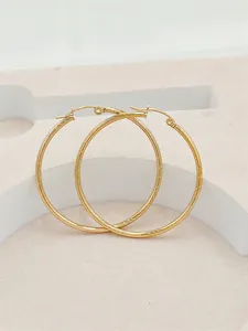 Detail view of large 24K gold plated hoop earrings with textured stripes for women