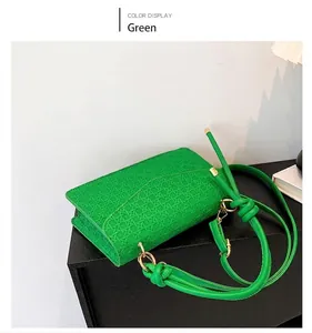 Detail shot of a vibrant green minimalist square crossbody bag with unique woven texture.