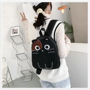 Cute black cat-themed canvas backpack worn by a student in a bright casual indoor setting