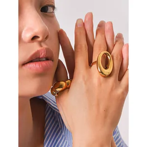 Élégante bague dorée ovale évidée portée par un mannequin asiatique en chemise rayée