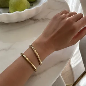 Detailed macro shot of elegant minimalist gold-plated stainless steel bangles on a wrist