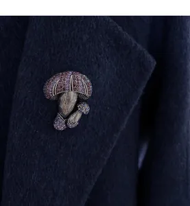 Detail of a vintage-style mushroom brooch with purple and pink rhinestones on a coat.