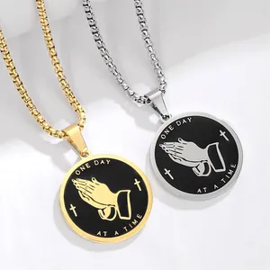 Close-up of stainless steel praying hands coin necklaces in gold and silver finishes.