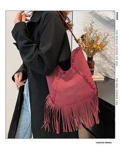 Detailed view of a bohemian red suede fringe shoulder bag with sun emboss and stud trim.