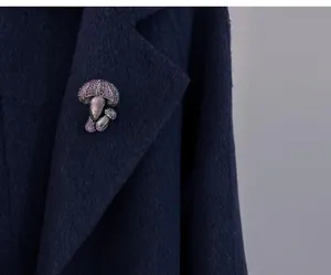 Close-up of a vintage mushroom brooch with purple rhinestones on a navy wool coat