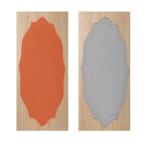 Vue détaillée de sets de table en lin brodés de forme irrégulière en orange et gris.