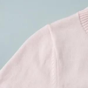 Primo piano di un cardigan in maglia rosa con cucitura fine sulla spalla e morbida