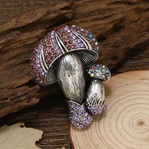 Vintage silver mushroom brooch set with purple and iridescent rhinestones on wood