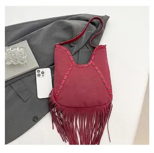 Detailed close-up of a bohemian fringe shoulder bag with metallic studs and sun emblem
