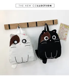 Detail view of two cute cat-shaped canvas backpacks hanging on a wooden wall hook