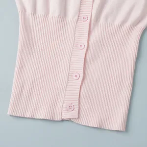Dettaglio ravvicinato del cardigan rosa in maglia con orlo a costine e bottoni