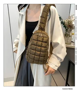 Dettaglio di un borsello trapuntato in nylon kaki abbinato a un trench bianco elegante.