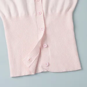 Dettaglio ravvicinato di un cardigan in maglia rosa con bordo a coste e bottoni coordinati