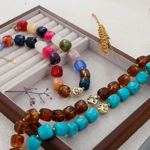 Vue macro détaillée de colliers de perles en résine bohème sur un plateau à bijoux.