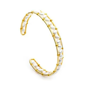 Detailed view of an 18K gold plated open cuff bracelet with irregular white stones.