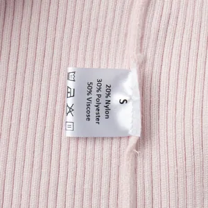 Primo piano dell'etichetta di cura su un cardigan in maglia rosa, taglia S, dettaglio