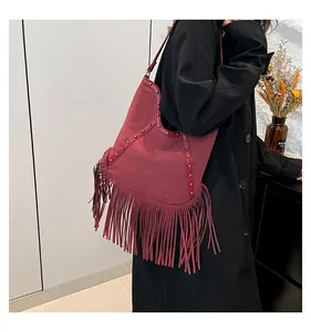 Side view of a vintage bohemian tote bag with long tassels and studs worn on shoulder.