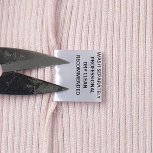 Vista dettagliata dell'etichetta di lavaggio di un cardigan in maglia rosa con istruzioni secco