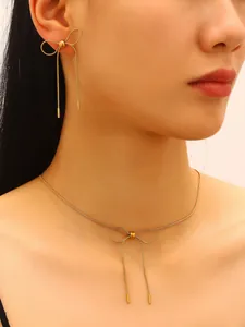Detail of elegant gold stainless steel bow knot necklace and earring jewelry set on model