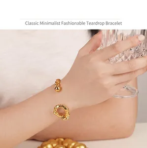 Detailed view of an irregular 18k gold plated open cuff bangle worn on a female wrist