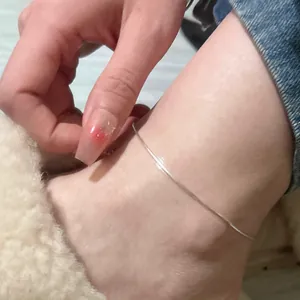 Detailed close-up of a minimalist 925 silver snake chain anklet worn on a woman ankle.