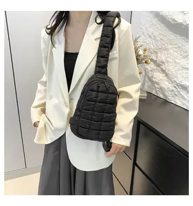 Dettaglio di borsa a tracolla in nylon trapuntato nero indossata sopra un blazer bianco