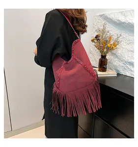 Retro bohemian burgundy suede shoulder bag featuring long fringes and rivet details.
