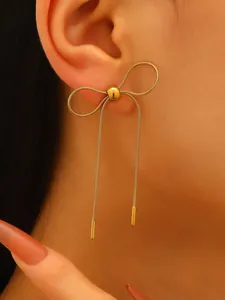 Detailed view of elegant gold-toned stainless steel bowknot stud earring on ear