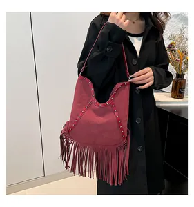 Close-up of bohemian style hobo bag with long fringe and embossed sun pattern.