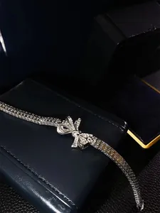 Close-up of silver bow-knot bracelet with micro-paved rhinestones on navy jewelry box