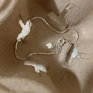 Detailed macro view of a minimalist S925 sterling silver snake chain anklet with heart charm