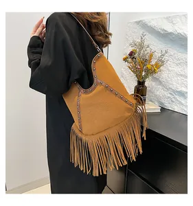 Detail view of Bohemian brown fringe hobo bag with metallic studs on model