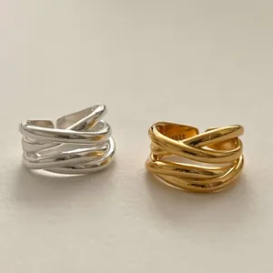 Detailed close-up of irregular minimalist crossover rings with high-light metallic finish