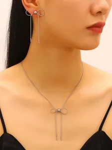 Elegantly crafted silver stainless steel bow-tie necklace and earring set on model.