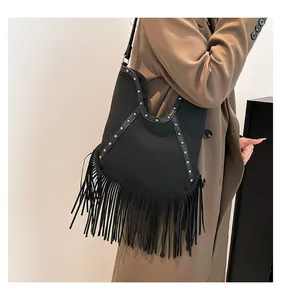 Close-up of vintage black bohemian fringe tote bag with metal studs and sun embossed detail