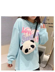 Detail view of a cute panda plush crossbody bag worn by a model in casual blue sweatshirt