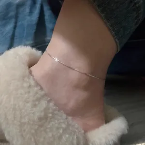 Detail view of a minimalist 925 silver snake chain anklet worn on a person's ankle