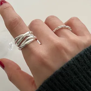 Macro detail view of a minimalist irregular silver cross ring with high gloss texture