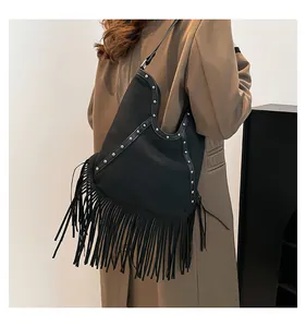 Black bohemian tassel shoulder bag with silver studs detail on a model.