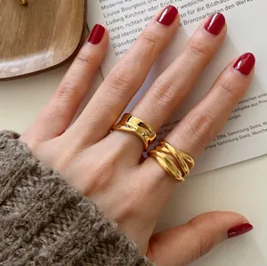 Close-up detail of irregular gold wave ring and triple-strand crisscross band on finger