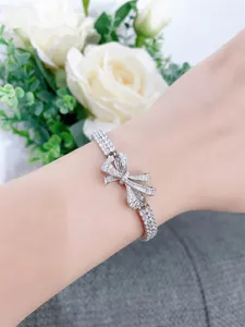 Elegant ribbon bow bracelet with sparkling simulated diamonds on wrist detail.